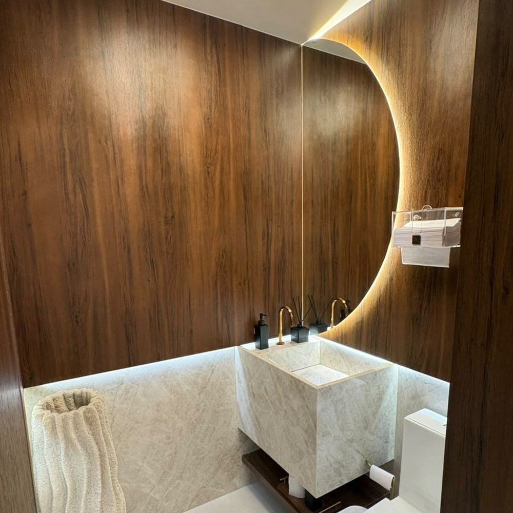 Lavabo do Instituto, com espelho redondo retroiluminado, metais dourados e cuba esculpida em mármore