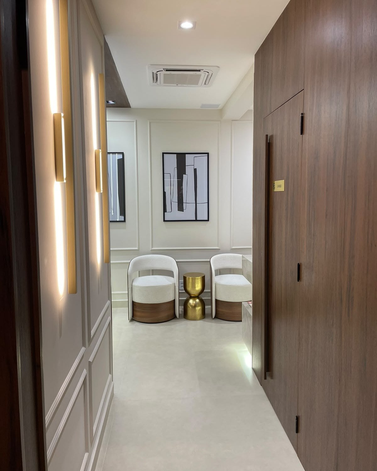 Corredor de entrada do Instituto Bosio Niederauer, com poltronas de espera e iluminação em dourado